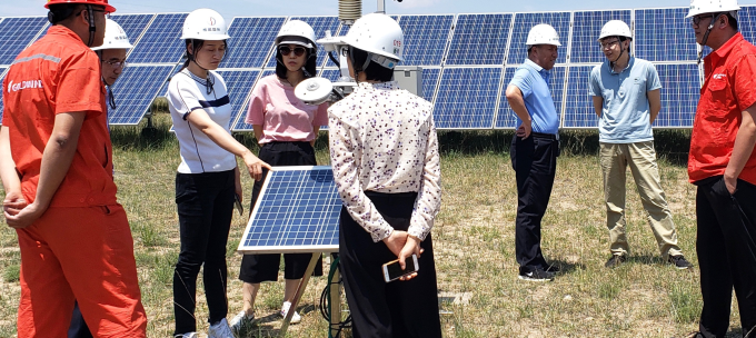 People in hard hats inspect a solar panel installation. 